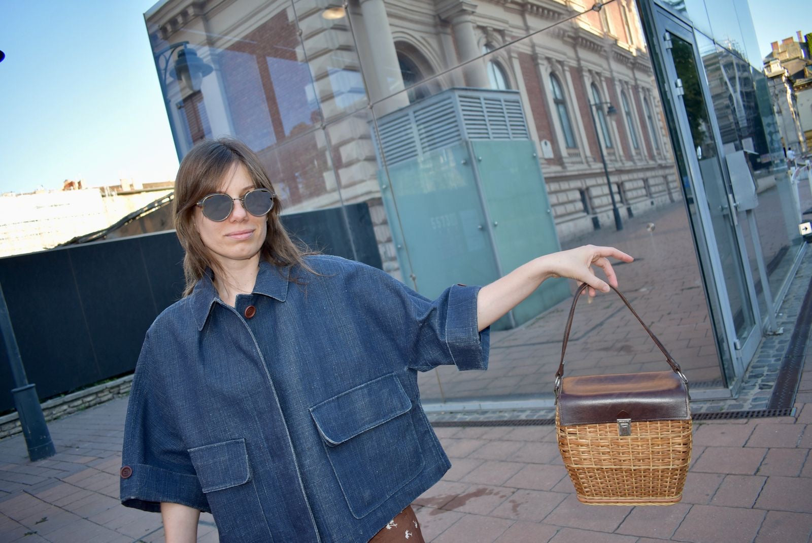 Woman holding a woven handbag on a city street